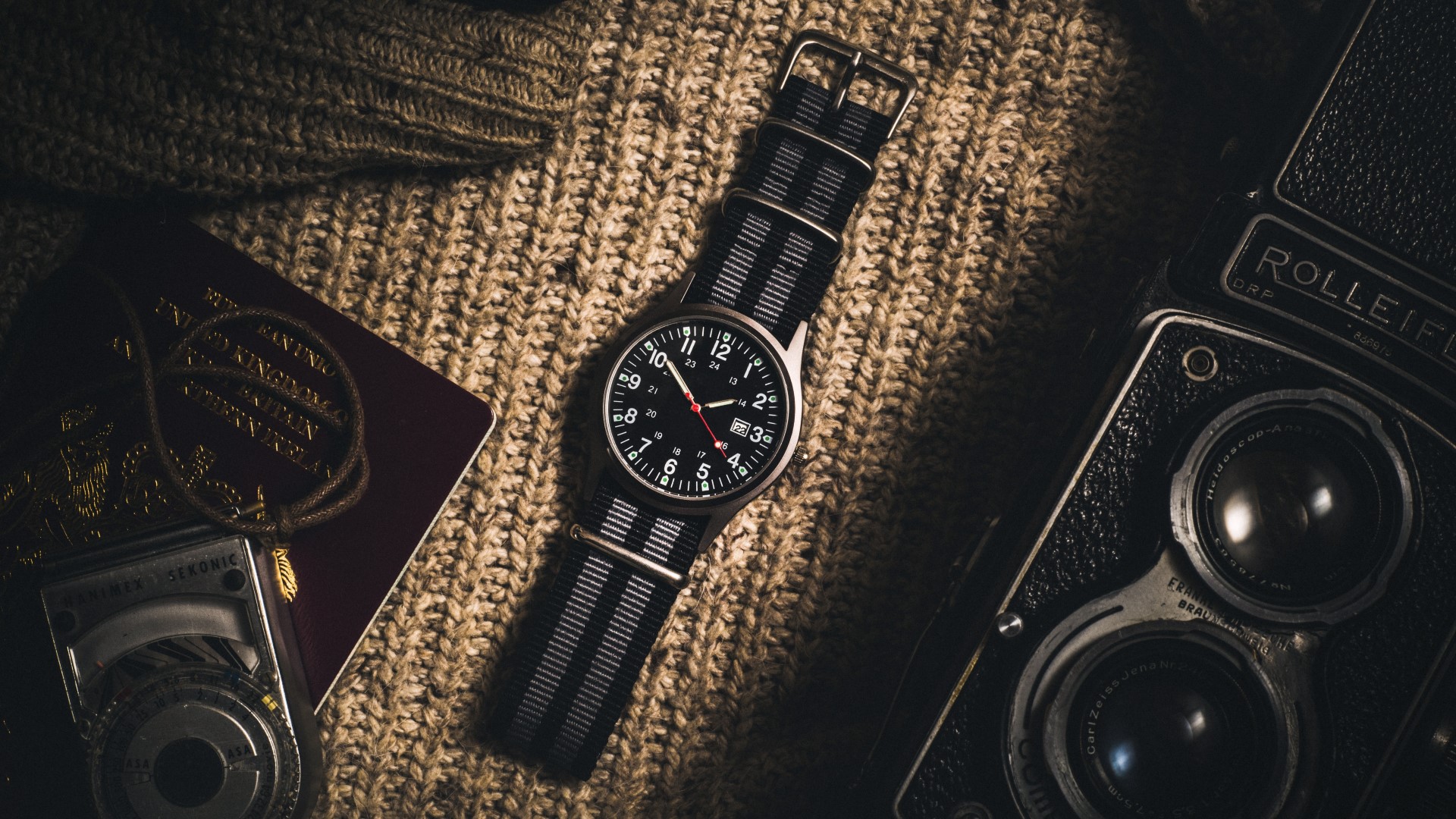 Un bodegón de una cámara vintage, un reloj y un pasaporte sobre un fondo de punto.
