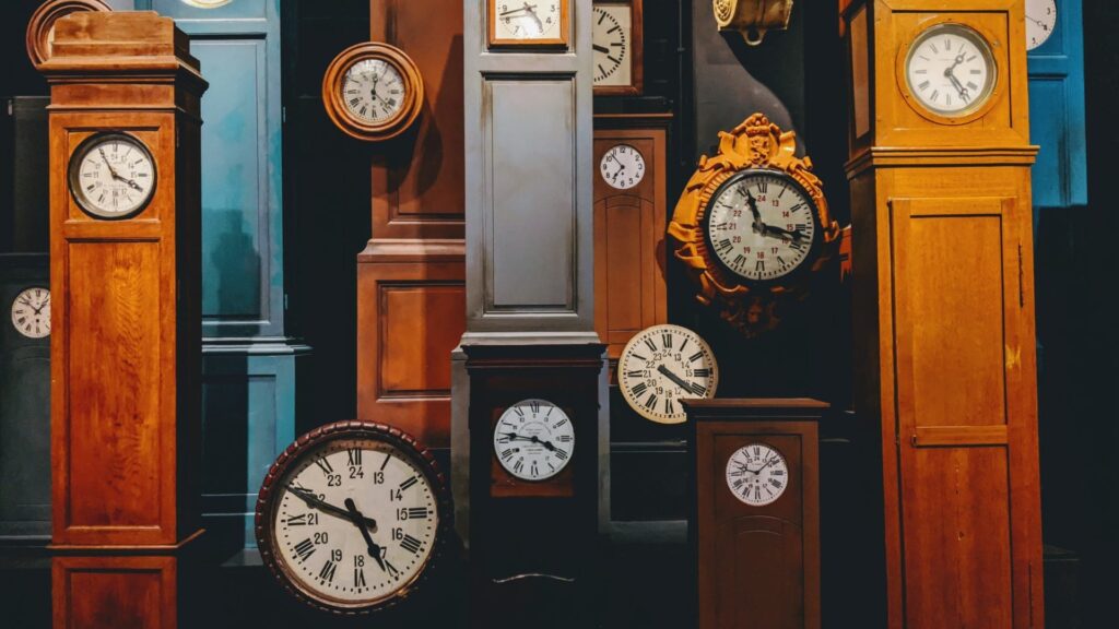 Una colección de relojes antiguos de diferentes estilos y tamaños en una habitación oscura.